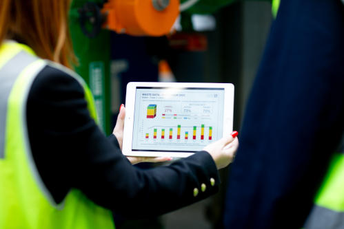 A person holding a tablet showing a waste management data graph at Collins Square