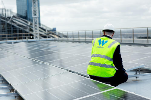 A Walker employee doing maintenance on a solar panel at Collins Square
