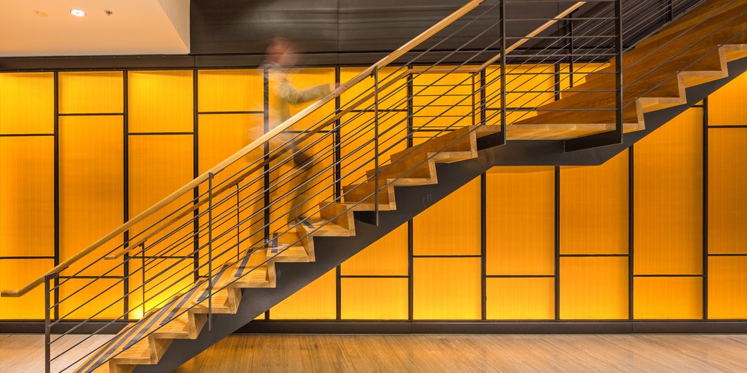 A staircase within an office of Tower 3 at Collins Square with a bright, yellow feature wall behind it